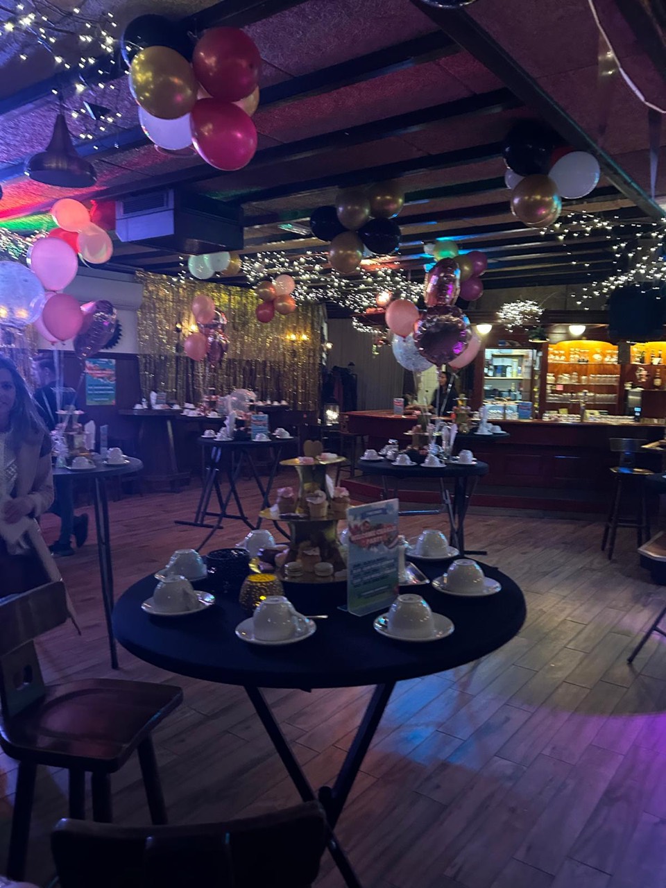 De feestzaal met ballonnen, lichtjes en gedekte statafels