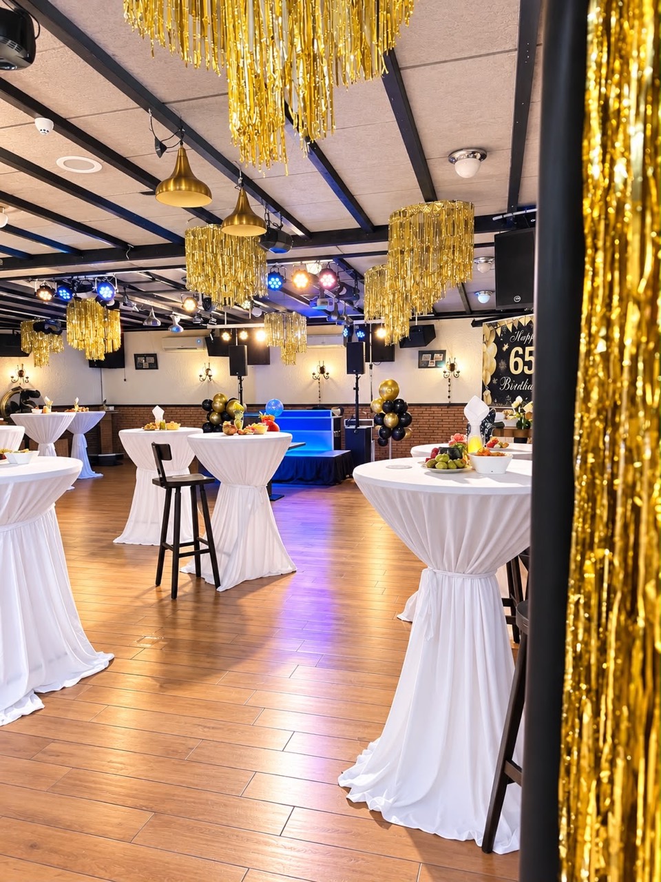 De feestzaal met gouden versiering, ballonnen en statafels met witte hoezen