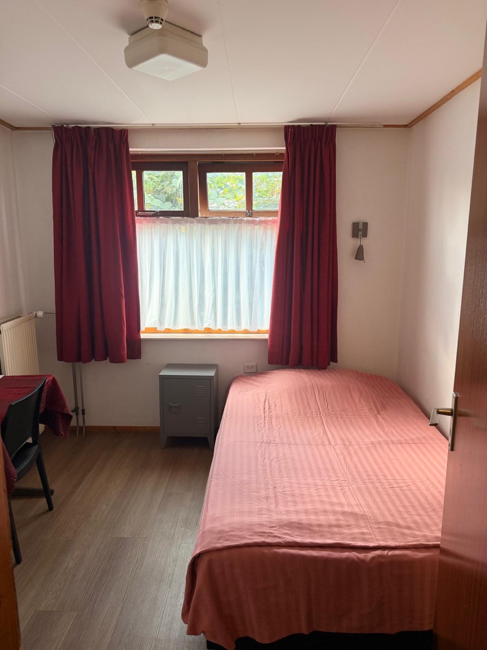 Een eenvoudig ingerichte hotelkamer met tweepersoonsbed