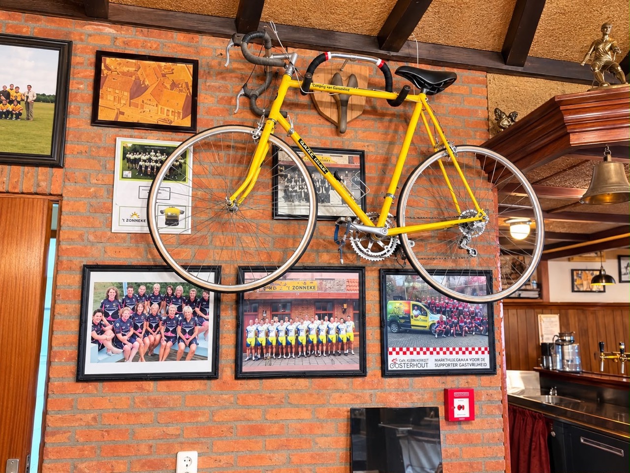 De gele racefiets tussen wielerherinneringen aan de muur